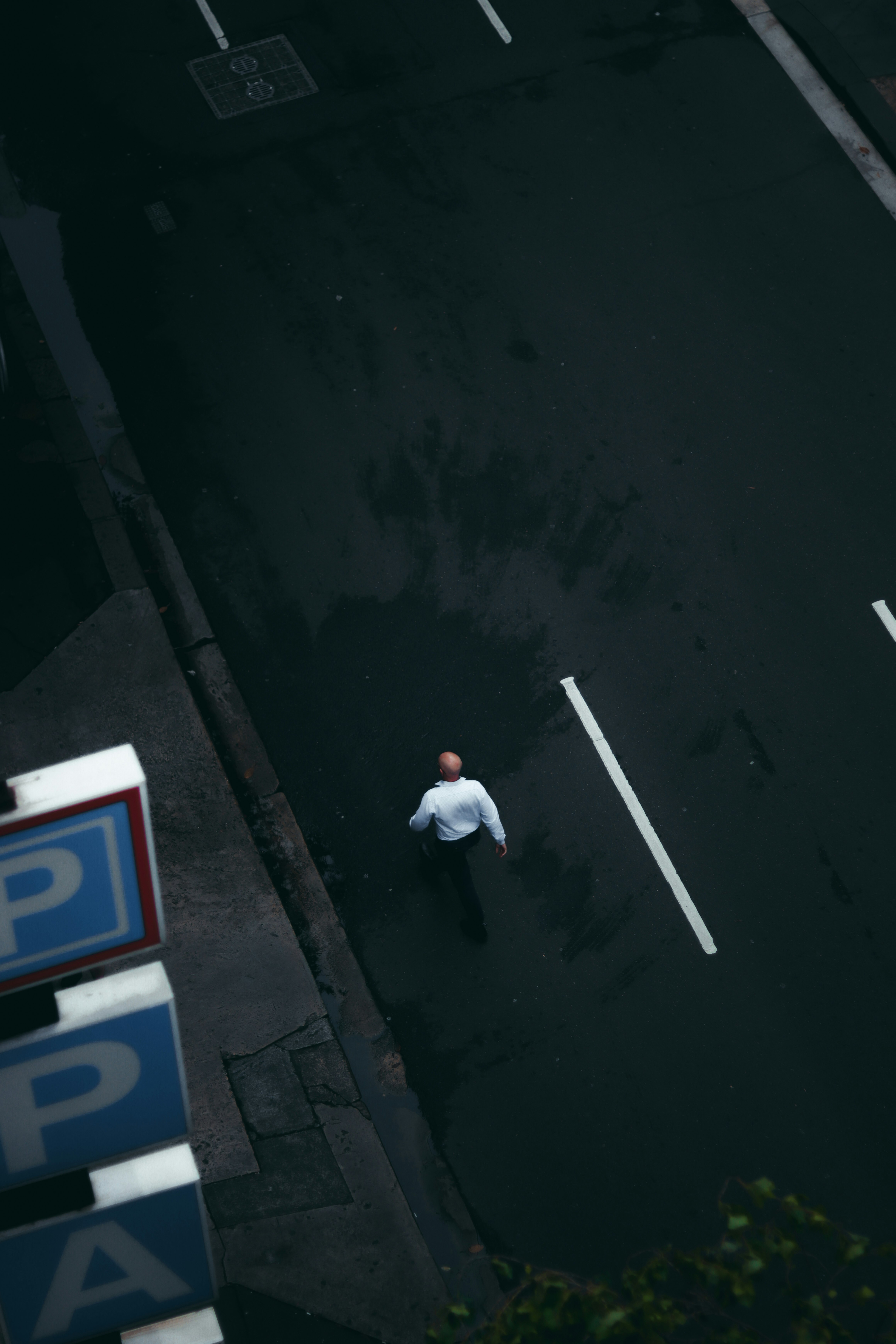 man in white shirt and black pants walking on sidewalk during daytime